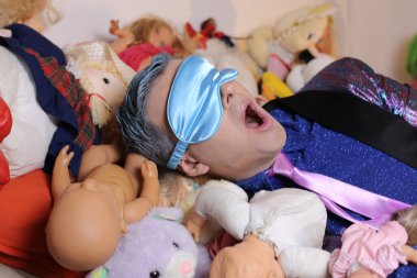 Yumuşak oyuncaklarla dolu yatakta takım elbiseli yakışıklı genç adamın yakın plan portresi.