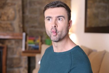 Dudaklarını buruşturan yakışıklı genç adamın yakın plan portresi.