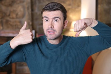 Yakışıklı genç adamın baş parmağını yukarı aşağı gösteren yakın plan portresi.