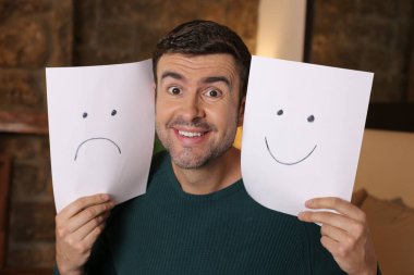 Elinde hüzünlü ve mutlu duygularla kağıtlar tutan yakışıklı bir gencin yakın plan portresi.