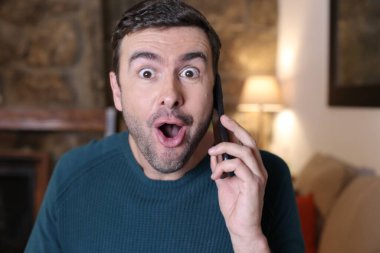 Evde telefonla konuşan duygusal genç adamın yakın plan portresi.