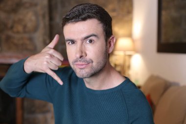 Kameraya telefon işareti yapan yakışıklı bir gencin yakın plan portresi.