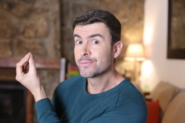 Kameraya el kol hareketi yapan yakışıklı genç adamın yakın plan portresi.