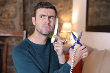 Telefonla konuşan ve makasla kabloyu kesen yakışıklı genç adamın yakın plan portresi.