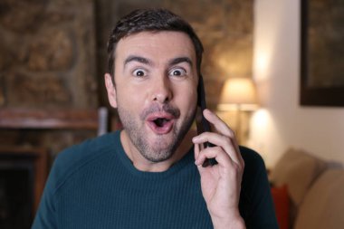 Evde telefonla konuşan duygusal genç adamın yakın plan portresi.