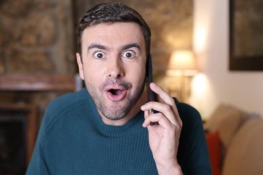 Evde telefonla konuşan duygusal genç adamın yakın plan portresi.