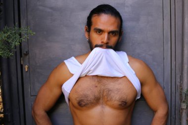 Beyaz gömleğini gri duvar arkasında çıkaran yakışıklı bir gencin yakın plan portresi.