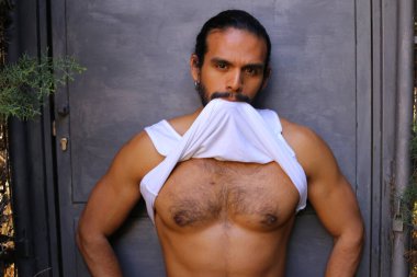 Beyaz gömleğini gri duvar arkasında çıkaran yakışıklı bir gencin yakın plan portresi.