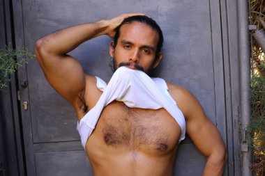 Beyaz gömleğini gri duvar arkasında çıkaran yakışıklı bir gencin yakın plan portresi.