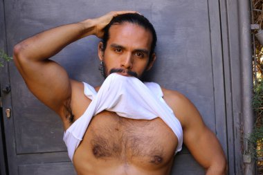 Beyaz gömleğini gri duvar arkasında çıkaran yakışıklı bir gencin yakın plan portresi.