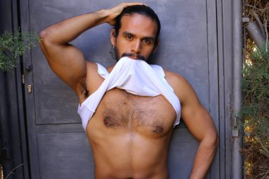 Beyaz gömleğini gri duvar arkasında çıkaran yakışıklı bir gencin yakın plan portresi.