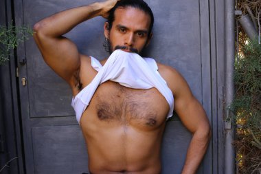 Beyaz gömleğini gri duvar arkasında çıkaran yakışıklı bir gencin yakın plan portresi.