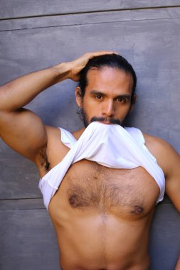 Beyaz gömleğini gri duvar arkasında çıkaran yakışıklı bir gencin yakın plan portresi.