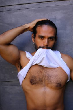 Beyaz gömleğini gri duvar arkasında çıkaran yakışıklı bir gencin yakın plan portresi.