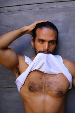 Beyaz gömleğini gri duvar arkasında çıkaran yakışıklı bir gencin yakın plan portresi.