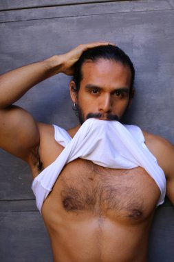 Beyaz gömleğini gri duvar arkasında çıkaran yakışıklı bir gencin yakın plan portresi.