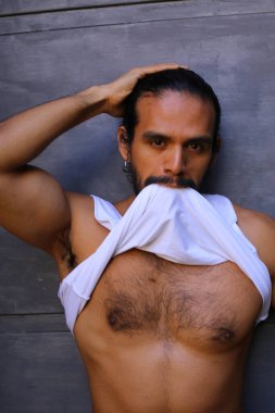 Beyaz gömleğini gri duvar arkasında çıkaran yakışıklı bir gencin yakın plan portresi.