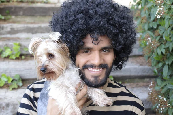 可愛い犬を屋外で保持しているアフロ髪型とハンサムな若い男のクローズアップ肖像画 — ストック写真