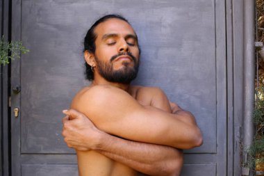 Gri duvardaki yakışıklı üstsüz genç adamın yakın plan portresi.