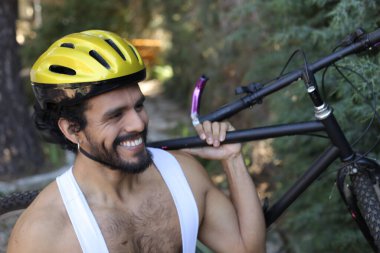 Dışarıda bisiklet tutan kasklı ve eşofmanlı yakışıklı genç adamın yakın plan portresi.