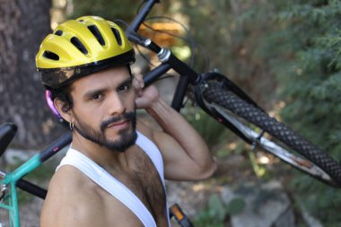 Dışarıda bisiklet tutan kasklı ve eşofmanlı yakışıklı genç adamın yakın plan portresi.