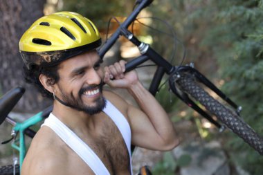 Dışarıda bisiklet tutan kasklı ve eşofmanlı yakışıklı genç adamın yakın plan portresi.