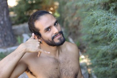 Yakışıklı üstsüz genç adamın açık havada telefon hareketlerini gösteren yakın plan portresi.