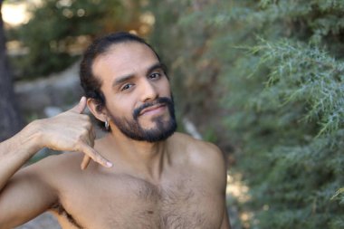 Yakışıklı üstsüz genç adamın açık havada telefon hareketlerini gösteren yakın plan portresi.