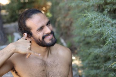 Yakışıklı üstsüz genç adamın açık havada telefon hareketlerini gösteren yakın plan portresi.