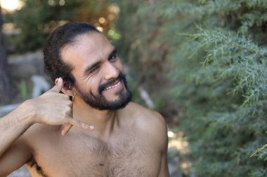 Yakışıklı üstsüz genç adamın açık havada telefon hareketlerini gösteren yakın plan portresi.