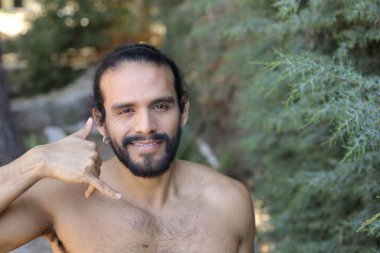 Yakışıklı üstsüz genç adamın açık havada telefon hareketlerini gösteren yakın plan portresi.