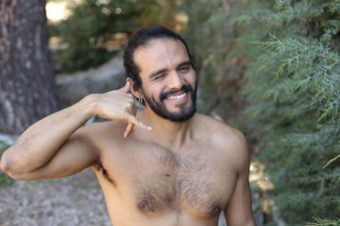 Yakışıklı üstsüz genç adamın açık havada telefon hareketlerini gösteren yakın plan portresi.