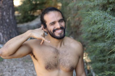 Yakışıklı üstsüz genç adamın açık havada telefon hareketlerini gösteren yakın plan portresi.