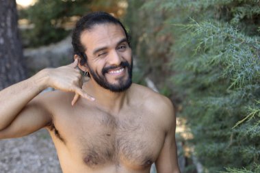 Yakışıklı üstsüz genç adamın açık havada telefon hareketlerini gösteren yakın plan portresi.