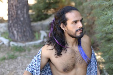 Açık havada renkli gömleği olan yakışıklı üstsüz genç adamın yakın plan portresi.