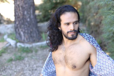 Açık havada renkli gömleği olan yakışıklı üstsüz genç adamın yakın plan portresi.