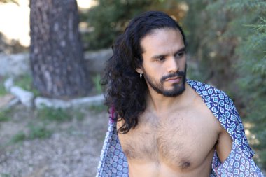 Açık havada renkli gömleği olan yakışıklı üstsüz genç adamın yakın plan portresi.