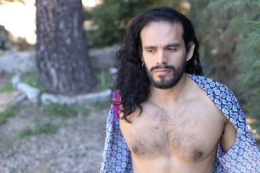 Açık havada renkli gömleği olan yakışıklı üstsüz genç adamın yakın plan portresi.