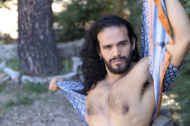 Açık havada renkli gömleği olan yakışıklı üstsüz genç adamın yakın plan portresi.