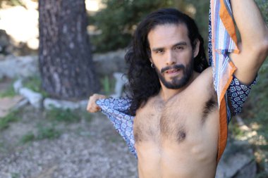 Açık havada renkli gömleği olan yakışıklı üstsüz genç adamın yakın plan portresi.