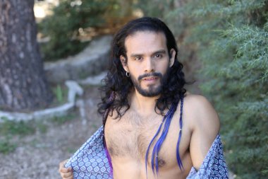 Açık havada renkli gömleği olan yakışıklı üstsüz genç adamın yakın plan portresi.