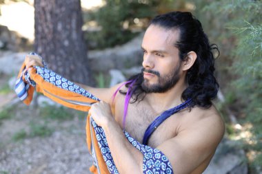 Açık havada renkli gömleği olan yakışıklı üstsüz genç adamın yakın plan portresi.