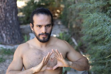 Yakından bakınca, elleri ile kalp şeklinde hareket eden yakışıklı, üstsüz genç bir adamın portresi.