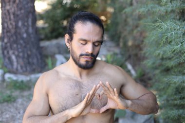 Yakından bakınca, elleri ile kalp şeklinde hareket eden yakışıklı, üstsüz genç bir adamın portresi.