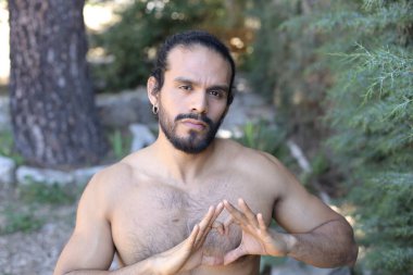 Yakından bakınca, elleri ile kalp şeklinde hareket eden yakışıklı, üstsüz genç bir adamın portresi.