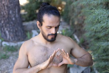 Yakından bakınca, elleri ile kalp şeklinde hareket eden yakışıklı, üstsüz genç bir adamın portresi.