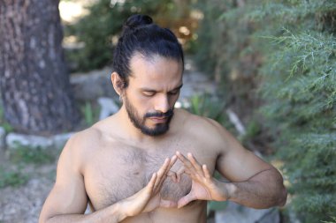 Yakından bakınca, elleri ile kalp şeklinde hareket eden yakışıklı, üstsüz genç bir adamın portresi.