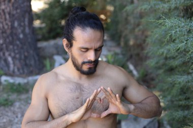 Yakından bakınca, elleri ile kalp şeklinde hareket eden yakışıklı, üstsüz genç bir adamın portresi.