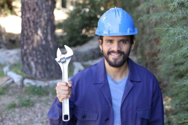 Açık havada ingiliz anahtarı takan yakışıklı bir tesisatçı portresi.