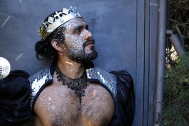 Kral tacı ve ayna topuyla şık bir karnaval kostümü giymiş yakışıklı genç adamın yakın plan portresi.